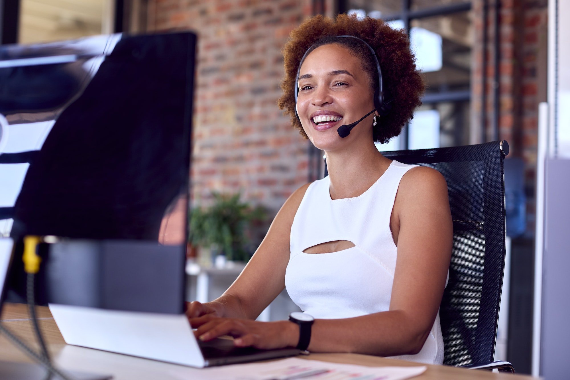 Businesswoman Wearing Headset At Computer In Customer Support Centre